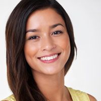 A brunette woman smiles confidently after a teeth-whitening treatment